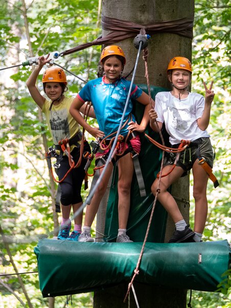 Three kids in the climbing forest with safety gear and helmets. | © WAP