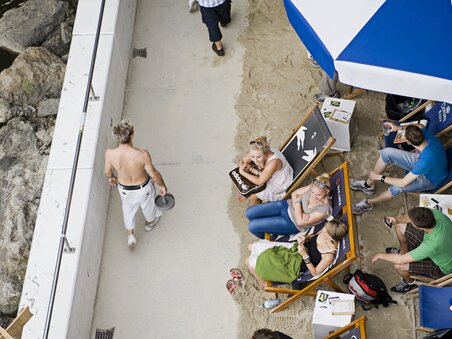 Menschen genießen die Sonne am Murufer, während andere vorbeigehen. | © Graz Tourismus - Toni Muhr
