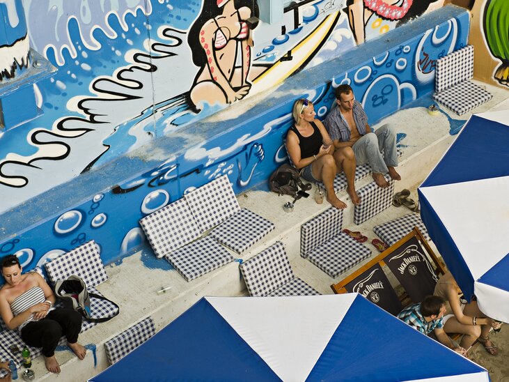 Blick auf eine Strandbar mit Graffiti und Sonnenliegen. | © Toni Muhr