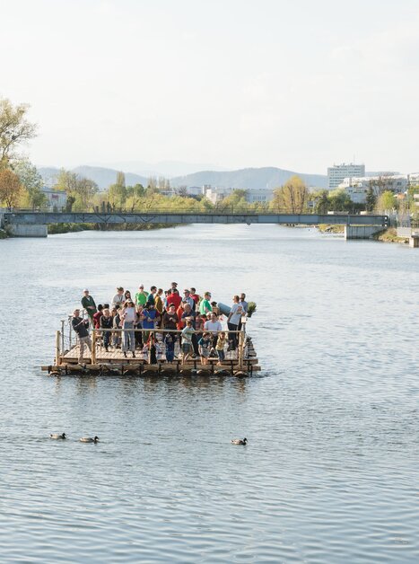 Gruppe von Menschen auf einem Floß auf der Mur in Graz. Entspannte Atmosphäre am Wasser. | © LippZahnschirm