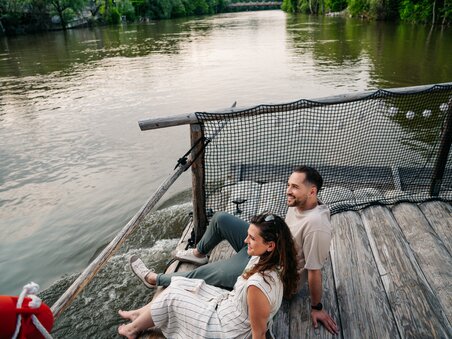 Paar sitzt am Fluss und genießt die Aussicht beim Floßfahren. | © Graz Tourismus - Mias Photoart