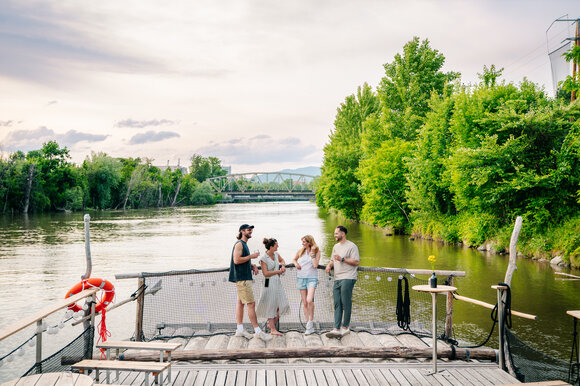 Group of friends enjoying time by the river in Graz, surrounded by trees. | © Graz Tourismus - Mias Photoart