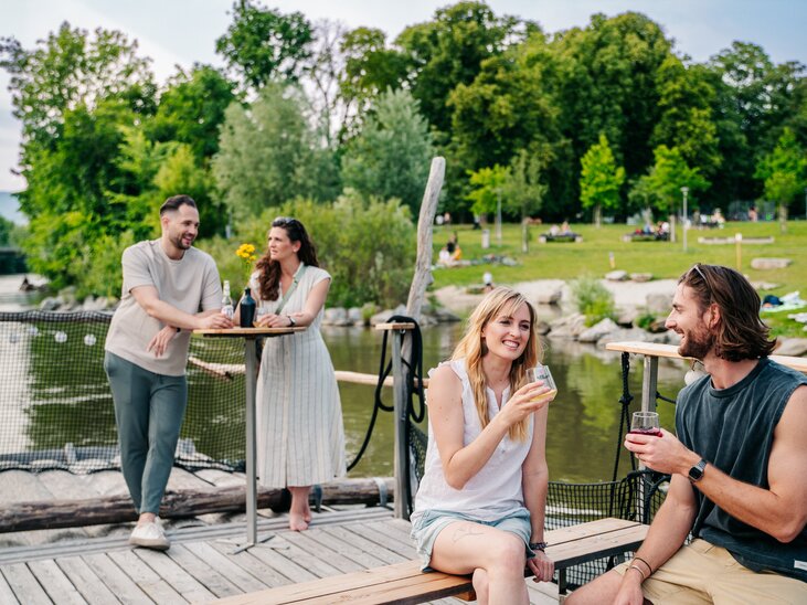 Gli amici si godono un drink su una zattera sul fiume Mur a Graz con il bel tempo. | © Graz Tourismus - Mias Photoart