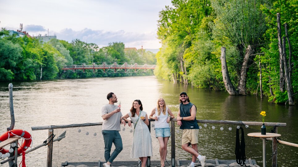 Four friends enjoy drinks on a raft on the Mur in Graz. | © Graz Tourismus - Mias Photoart