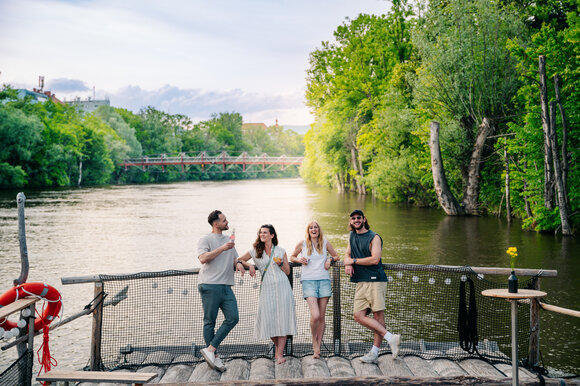 Four friends enjoy drinks on a raft on the Mur in Graz. | © Graz Tourismus - Mias Photoart