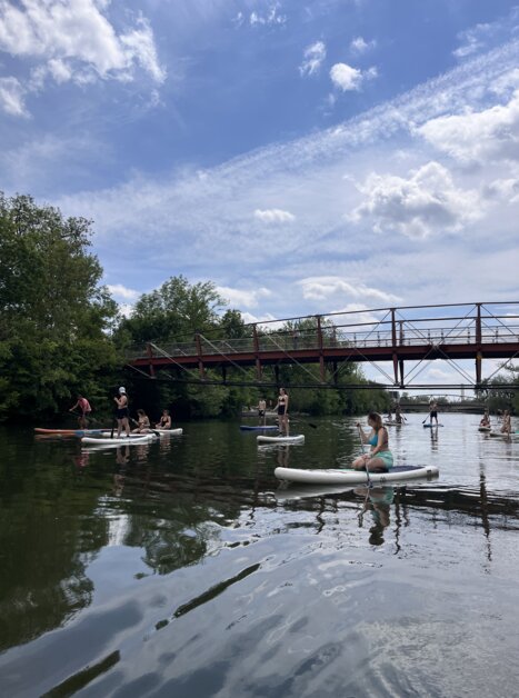 Paddler auf der Mur in Graz vor einer Brücke an einem sonnigen Tag. | © Die Flößerei