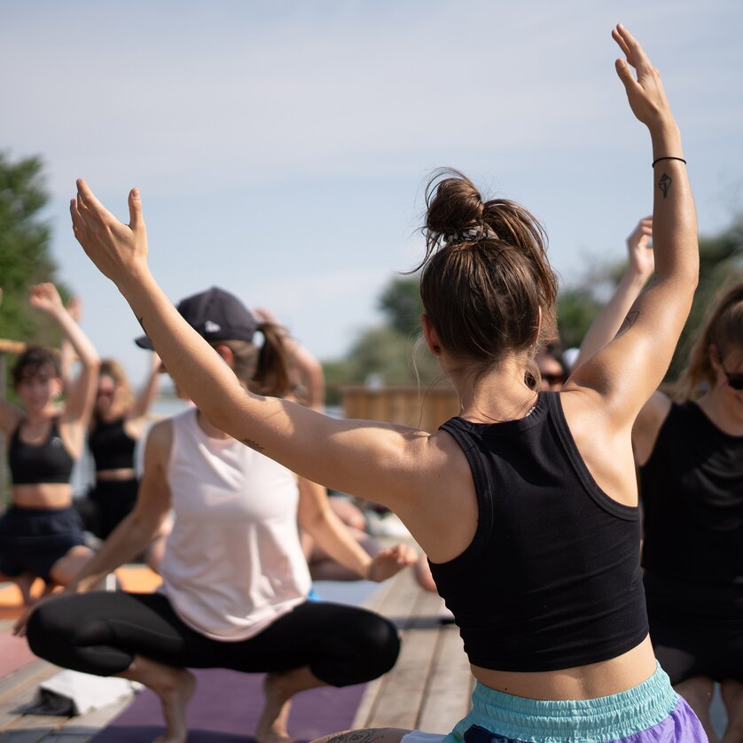 A group of people is taking part in a yoga class on a raft on the Mur River in Graz, offered by “Der Flößerei”. | © Robert Supnig