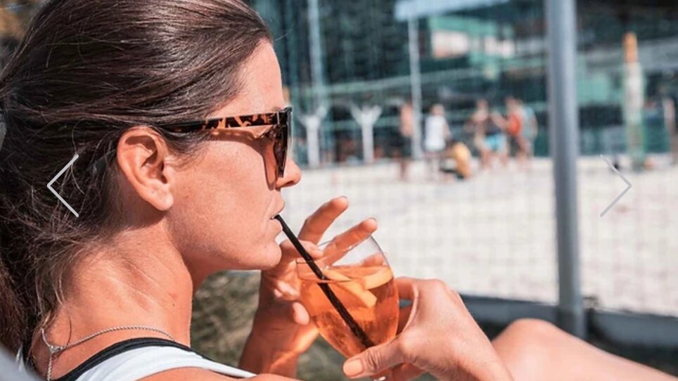 Entspannte Frau am Beachvolleyballplatz mit Drink in der Hand. | © Mur Beach - Ingo Gruber