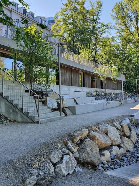 Die gepflasterte Uferpromenade entlang der Mur mit gestuften Treppen und modernen Gebäuden. | © Kajak Club Graz