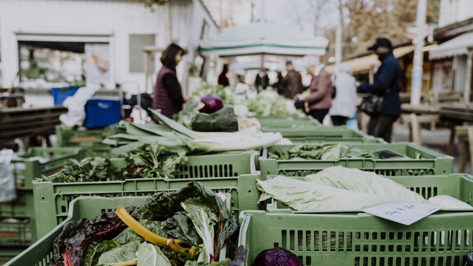 Vegetables at a market, with visitors in the background. | © Nina Söntgerath - Reisehappen
