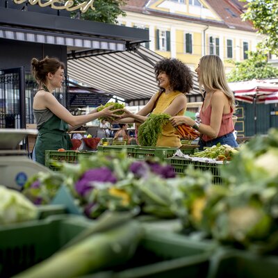Two women buying fresh vegetables at the Kaiser Josef Market in Graz. | © Graz Tourismus - Tom Lamm