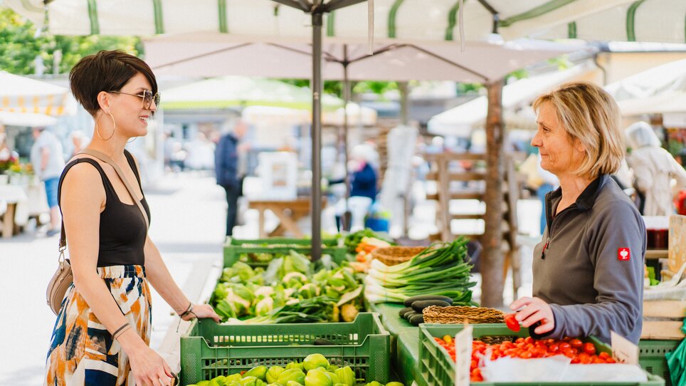 Kundin und Verkäuferin am Kaiser Josef Markt in Graz, umgeben von frischem Gemüse. | © 5komma5sinne - MotionAds