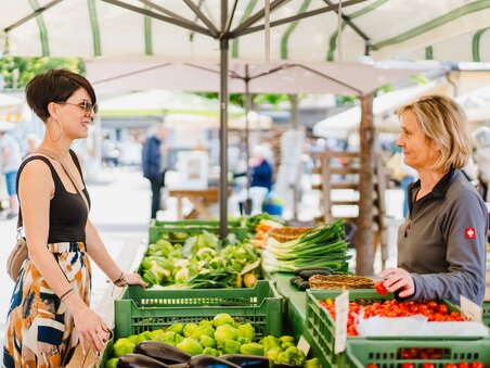 Customer and saleswoman at the Kaiser Josef market in Graz, surrounded by fresh vegetables. | © 5komma5sinne - MotionAds