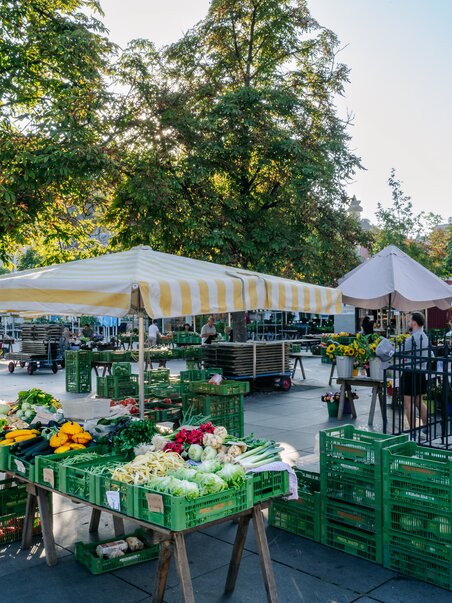 Mercato con verdure colorate e stand sotto ombrelloni a Graz. | © Graz Tourismus - Mias Photoart