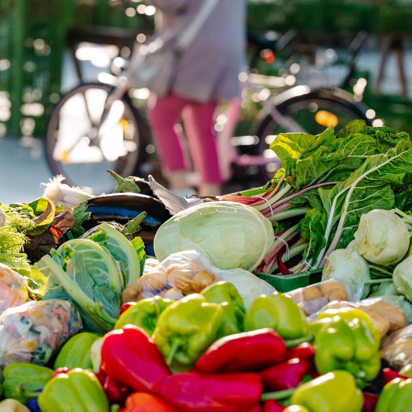 Bunte Gemüsevielfalt auf dem Bauernmarkt am Lendplatz in Graz - im Hintergrund eine Radfahrerin. | © Graz Tourismus - Mias Photoart