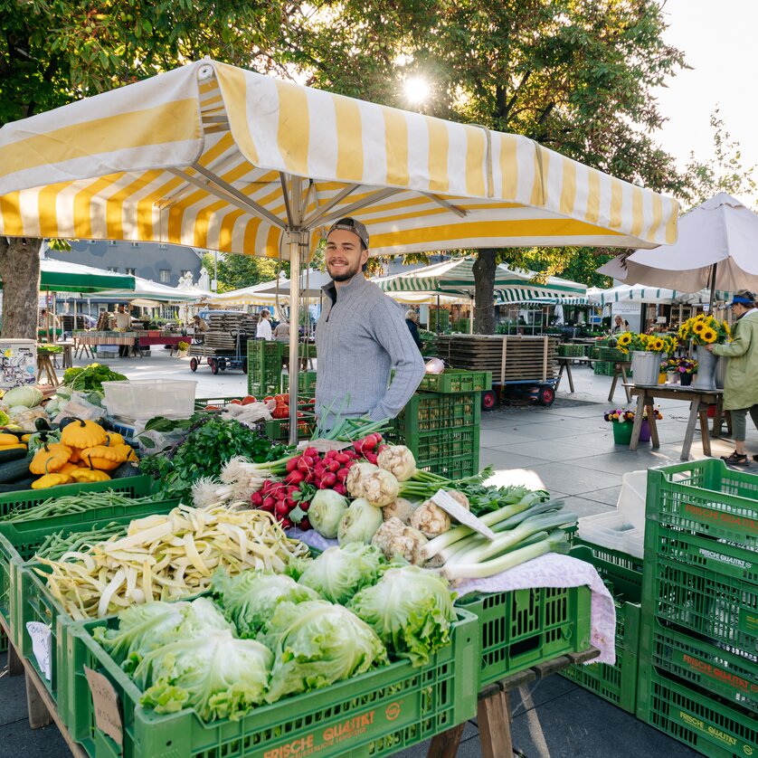 Lebendige Marktszene mit frischem Gemüse und Verkäufer in Graz. | © Graz Tourismus - Mias Photoart