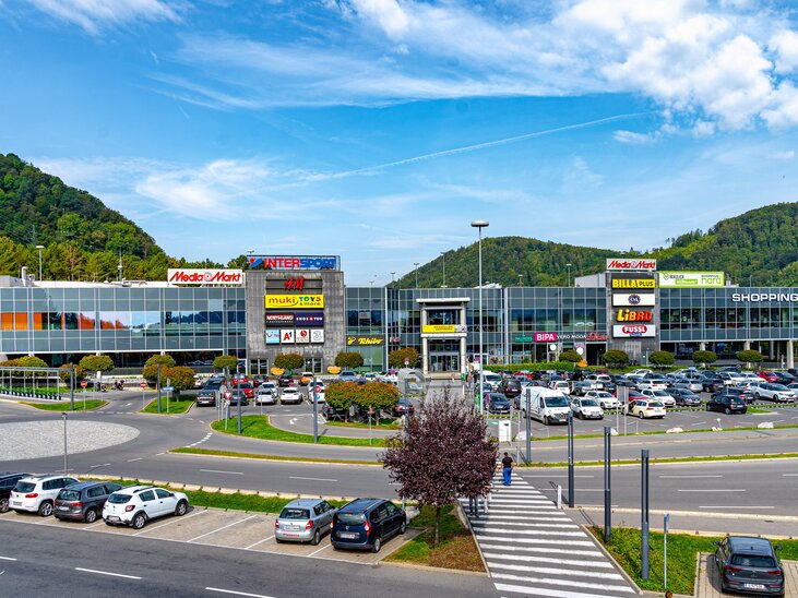 Modernes Einkaufszentrum mit Geschäften und Parkplatz. | © RIPIX