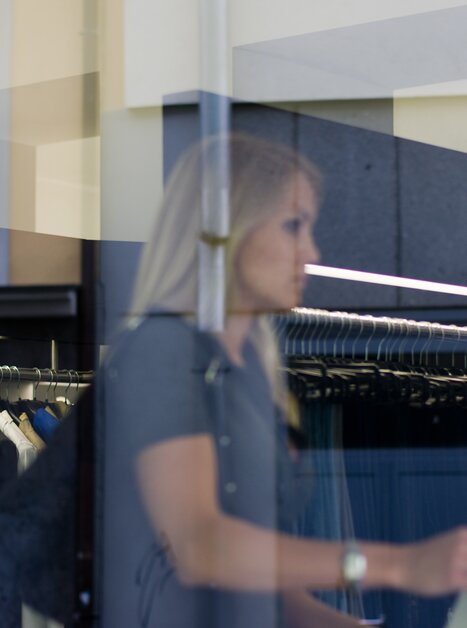 Spiegelung einer Frau in einem Schaufenster, die in einem Modegeschäft einkauft. | © Graz Tourismus - Hans Wiesenhofer