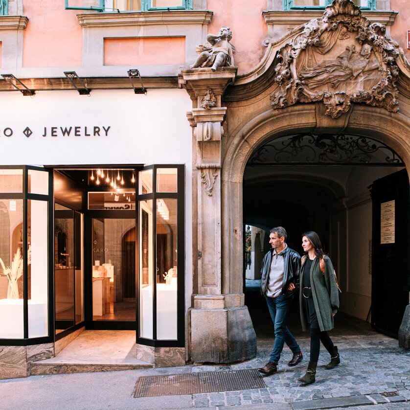 Couple walking in Graz in front of a jewelry store with a window display. | © Graz Tourismus