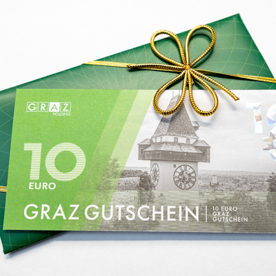 Ein Graz Gutschein im Wert von 10 Euro, dekoriert mit einer goldenen Schleife. | © Graz Tourismus - Harry Schiffer