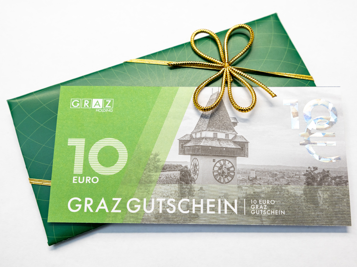 A Graz coupon worth 10 euros, decorated with a golden ribbon. | © Graz Tourismus - Harry Schiffer