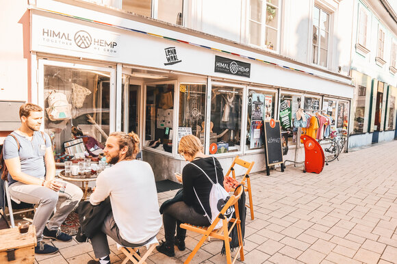 Drei Personen sitzen vor einem Geschäft im Lendviertel in Graz. | © Janet Newenham - Journalist On The Run