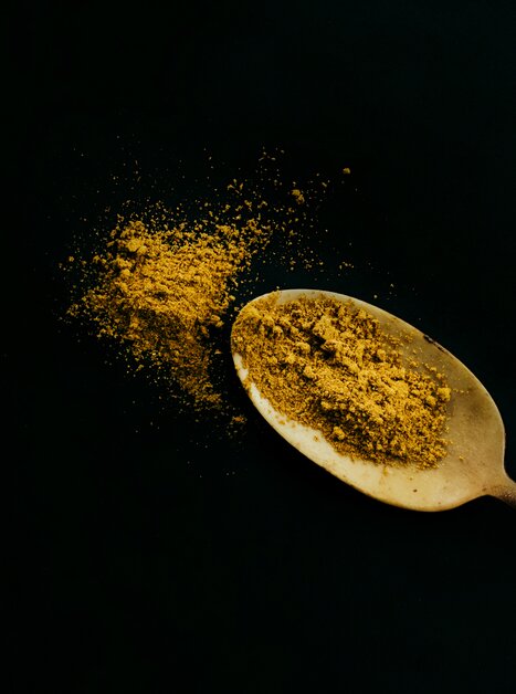 Ein Holzlöffel mit gemahlenem Gewürz auf schwarzem Hintergrund. | © Lupi Spuma