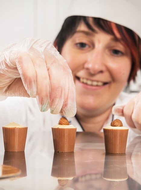 Donna che decora cioccolatini presso Eckhards Confiserie. | © Eckhards Confiserie I Graz