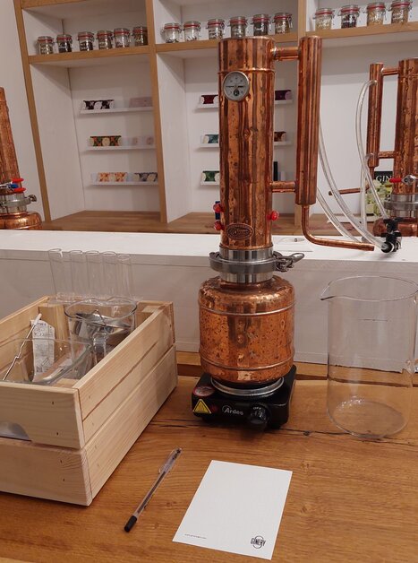 A copper distillery with glass containers and accessories in the background. | © The Ginery