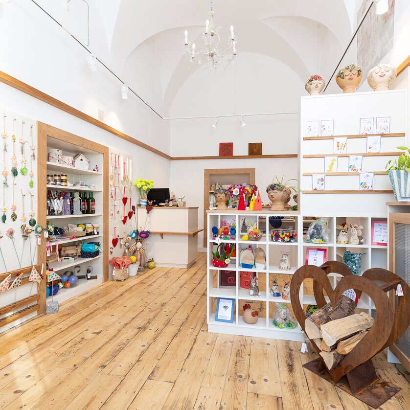 Innenansicht des HERZLich Ladens mit bunten Produkten und Holzfußboden. | © Willi Moertl