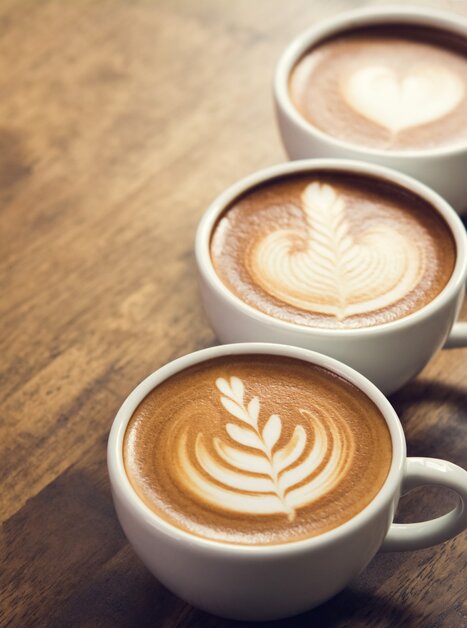 Drei Tassen Kaffee mit Latte Art auf einem Holztisch. | © Pixabay