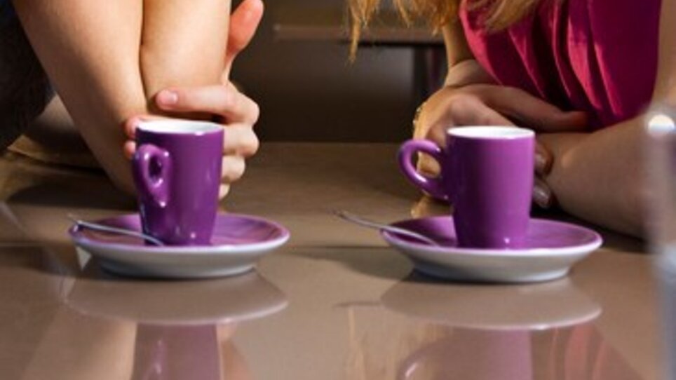 Two small purple coffee cups on a table, hands are intertwined. | © Graz Tourismus - Toni Muhr