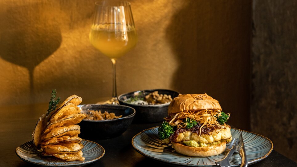 Un delizioso hamburger con contorni e vino in un ristorante. | © Lucija Novak