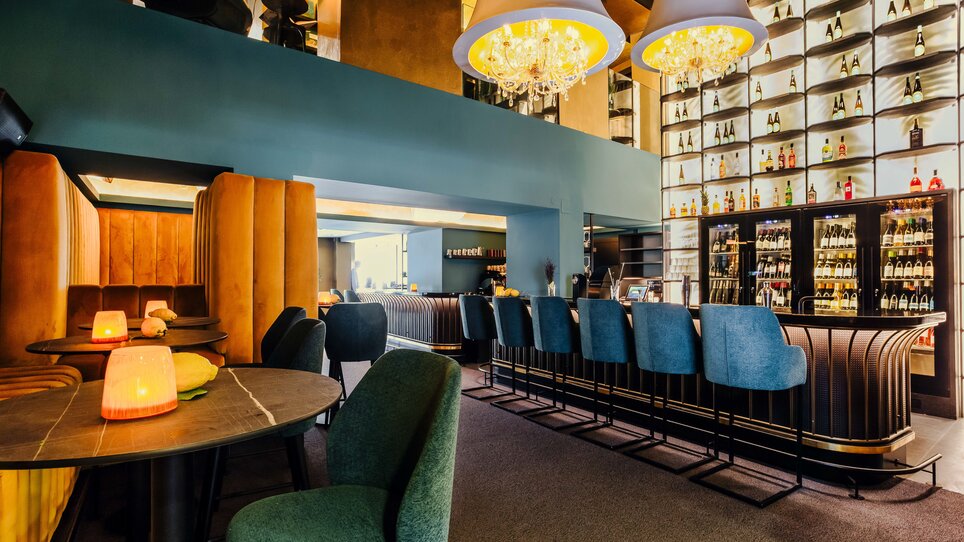 Bar elegante con aree salotto stilose e scaffali di liquori illuminati. | © Simon Bauer
