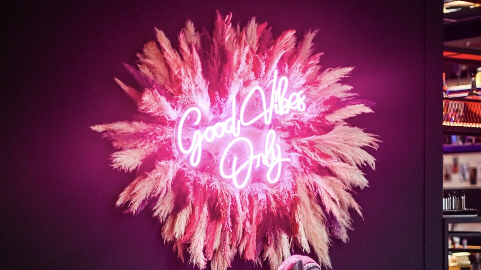 Stylischer Innenraum mit Neonlicht 'Good Vibes Only' und gemütlichen Sitzmöglichkeiten. | © Bonbon
