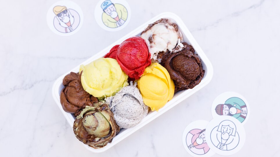 Eine Auswahl an bunten Eiskugeln in einer Schale mit Stickern. | © Eisperle - Stiefkind Fotografie