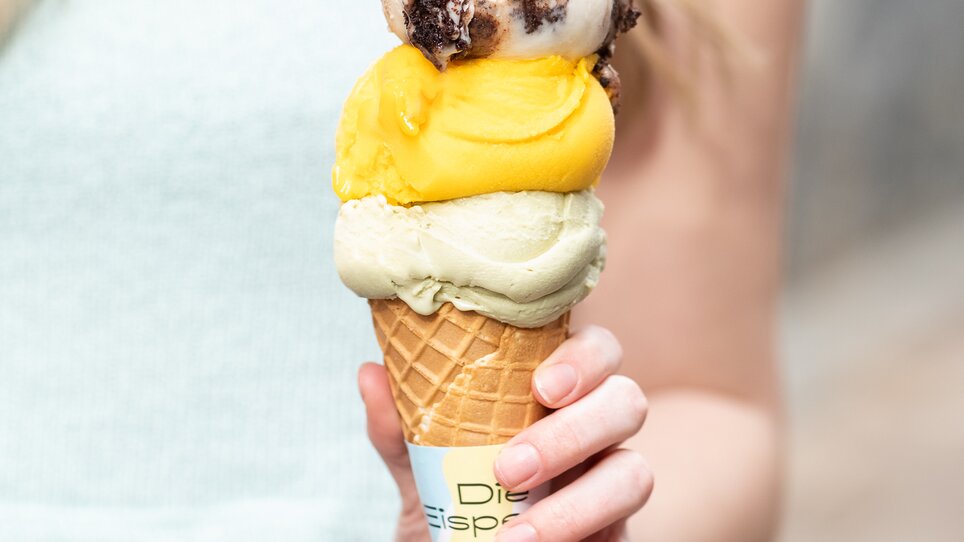 Ein junger Mensch hält ein Eiswaffel mit drei Kugeln Eis. | © Eisperle - Stiefkind Fotografie