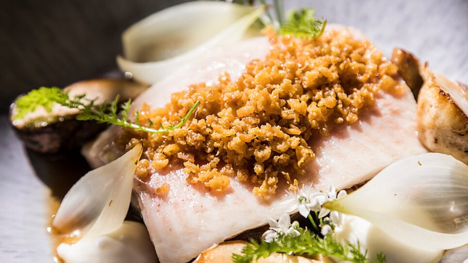 Pesce grigliato con croccante, servito con cipolle e erbe. | © Genießerei am Markt