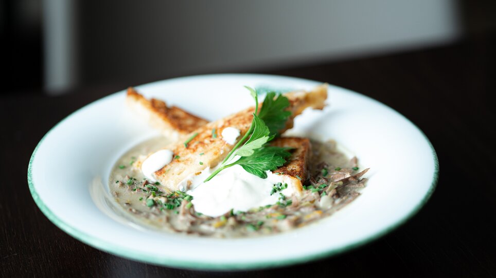 A plate of grilled fish with a creamy sauce, garnished with herbs. | © Tina Szabo