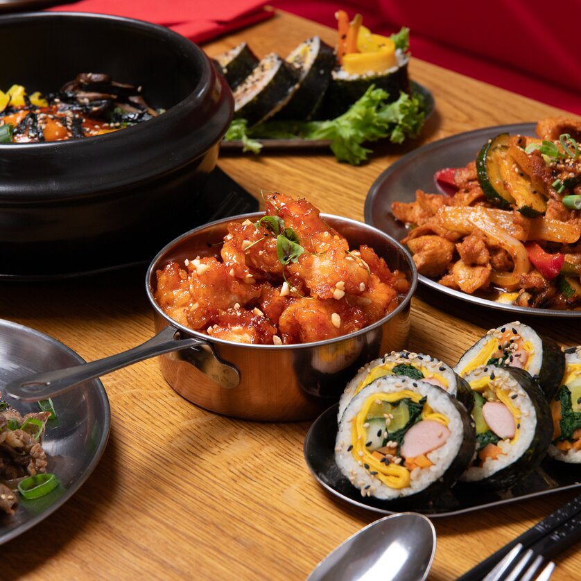 Colorful Asian dishes on a table, including sushi and stir-fried foods. | © Gogi KG