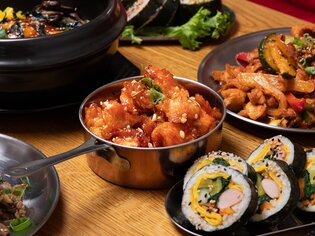 Bunte asiatische Gerichte auf einem Tisch, darunter Sushi und gebratene Speisen. | © Gogi KG