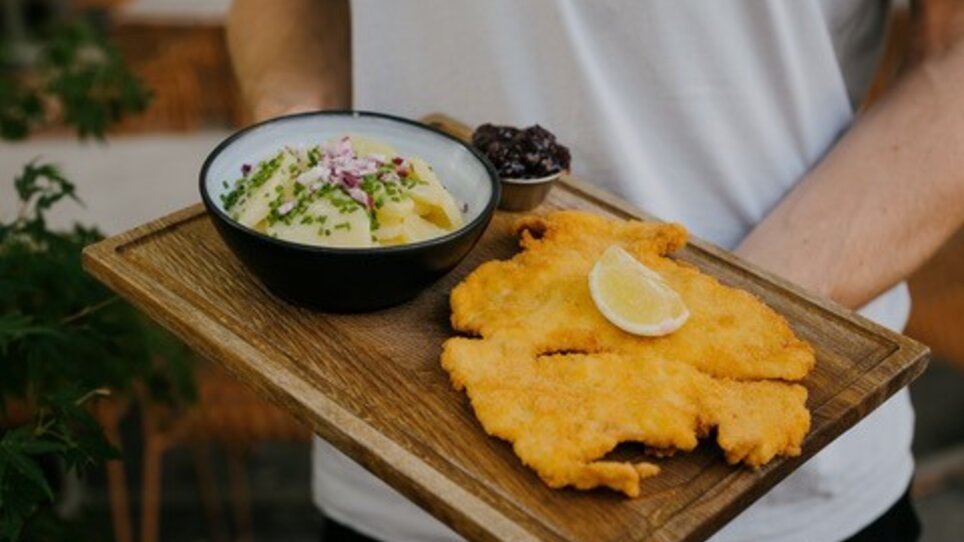 Fried schnitzels with lemon and side salad on a wooden plate. | © Dragan Dok - KLYO Graz
