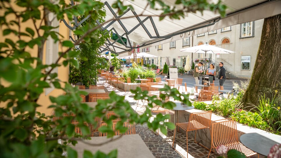 Cozy outdoor terrace of KLYO featuring plants and guests in Graz. | © mpview