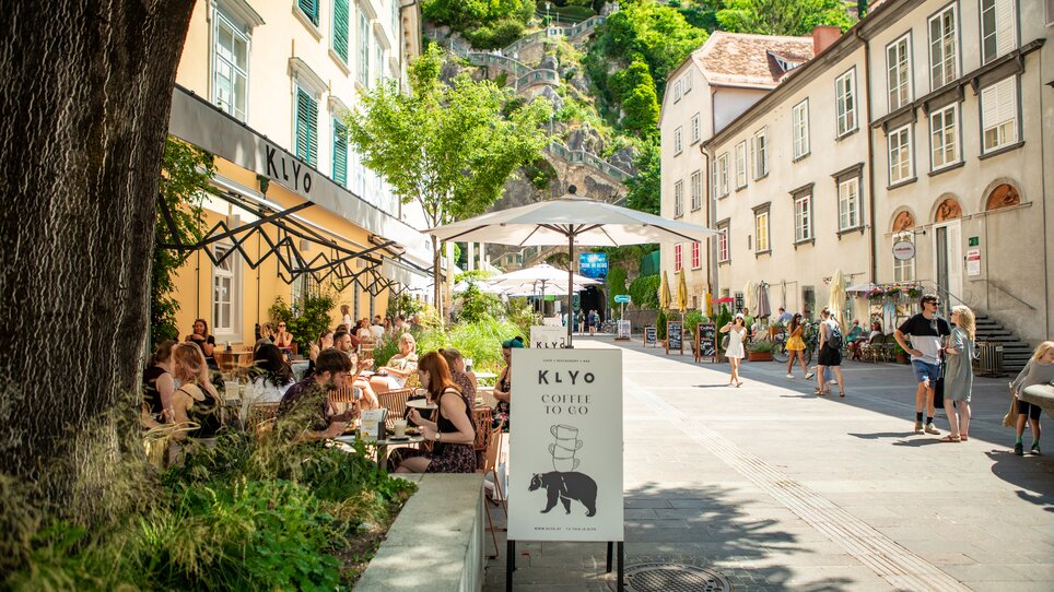 Cosy restaurant on Schlossbergplatz in Graz with guests and green surroundings. | © mpview