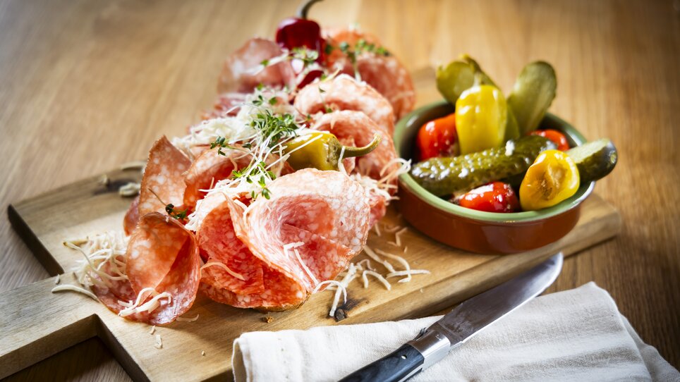 Piatto con salame, formaggio, sottaceti e peperoni su un tagliere di legno. | © Kaiser Greissler - Werner Krug