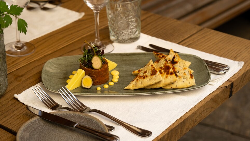 Beef Tatar - elegant dekoriert mit Gemüse und Brot als Beilagen auf einem Teller. | © Benjamin Kern