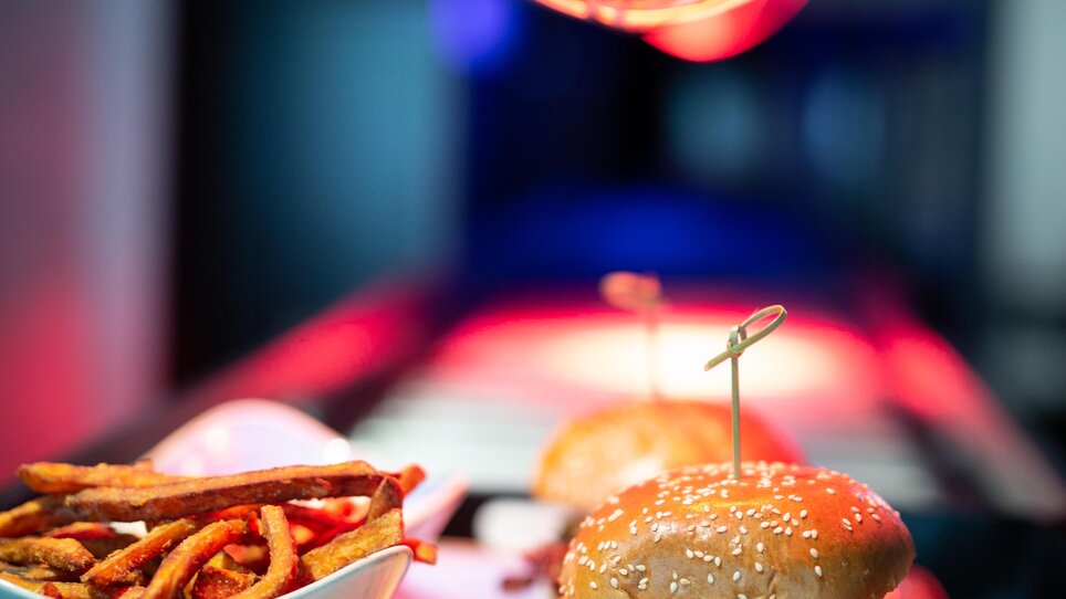 Un hamburger con patatine, illuminato sotto una lampada termica. | © The Guardians