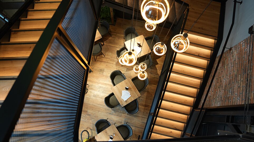 Area ristorante moderna con tavoli in legno e lampade sospese. | © The Guardians