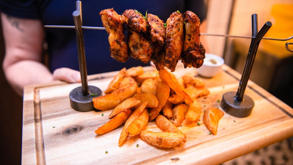 A plate with grilled chicken and potato wedges.