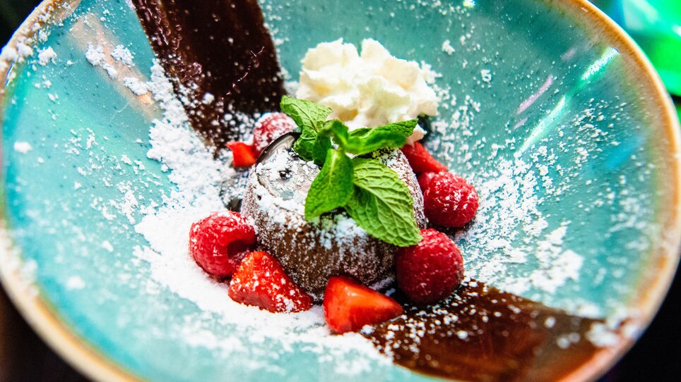 Delicious chocolate cake with berries and cream in a colorful bowl.